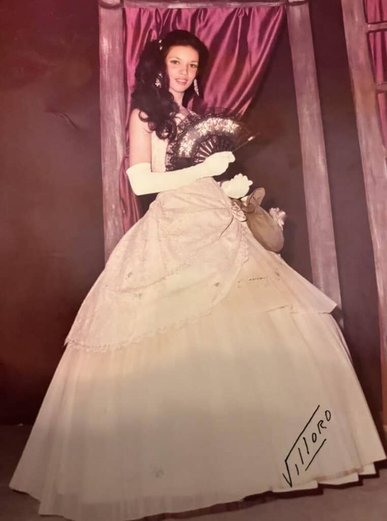 Elegant vintage woman in a ball gown holding a fan, 1950s style.