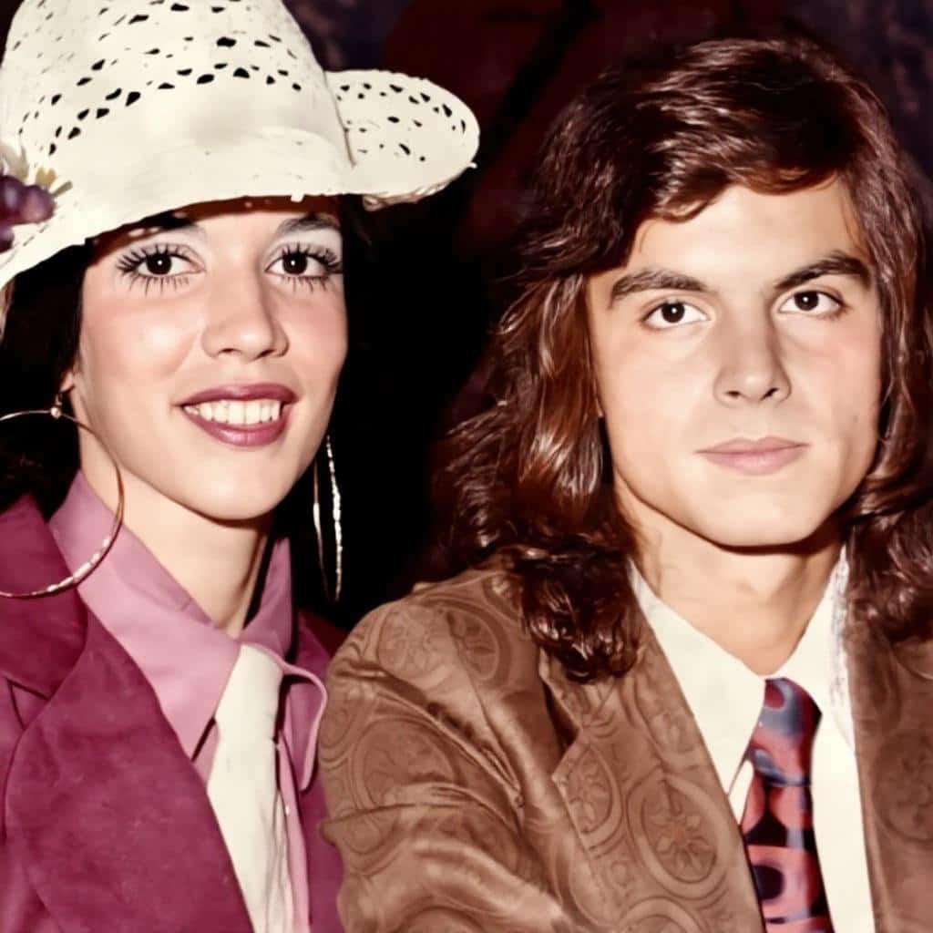 Vintage couple in 1970s fashion smiling at the camera.
