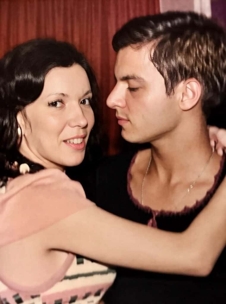 Young couple dancing closely at a social event, smiling and enjoying each other's company.